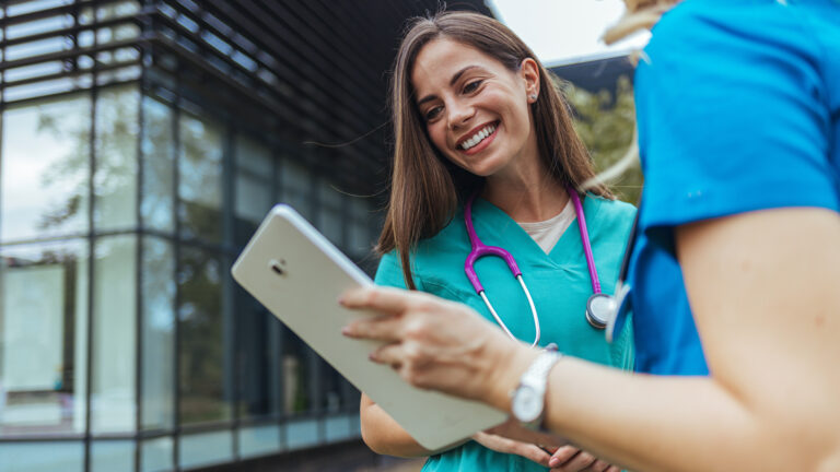 Researching news on a specific disease. Shot of two medical practitioners using a digital tablet together in a hospital. Healthcare staff having discussion in a hallway of private clinic.