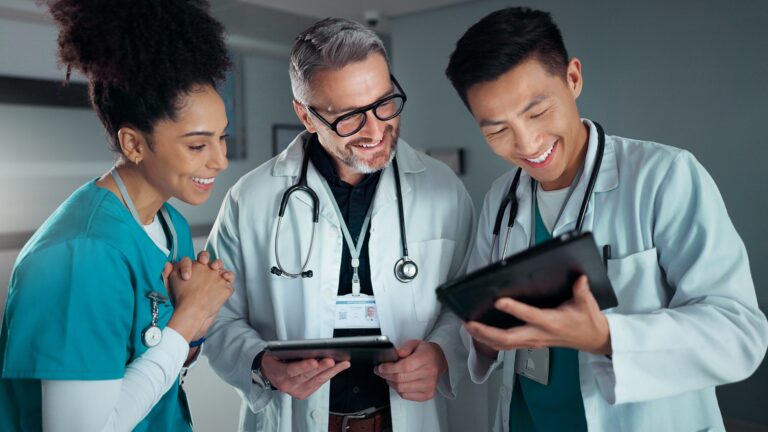 two guys looking at ipad and a healthcare worker smiling