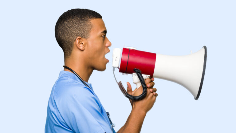 Surgeon doctor man shouting through a megaphone to announce something in lateral position on isolated background